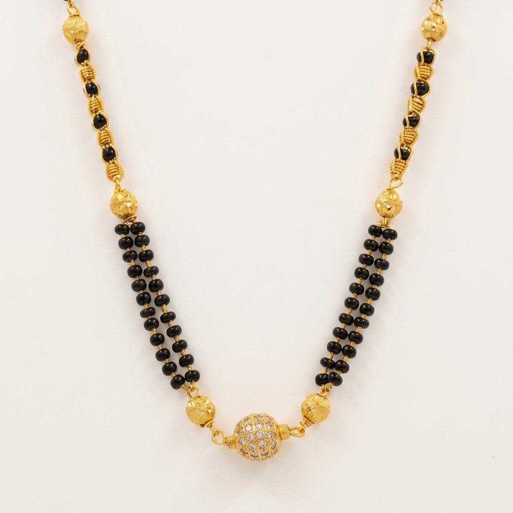 Close-up of gold-tone and black bead mangalsutra chain with central crystal-studded bead
