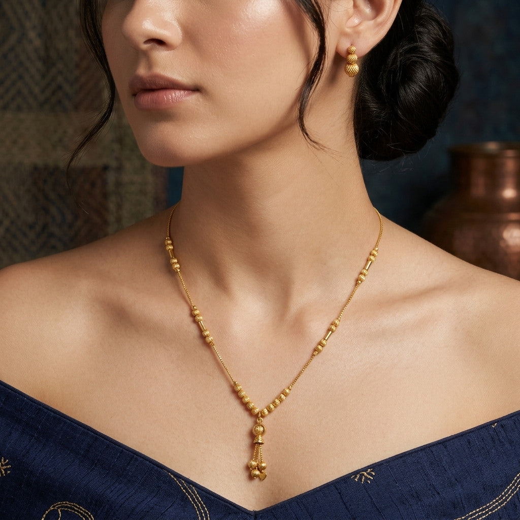 Close-up of gold-tone beaded chain necklace worn by model