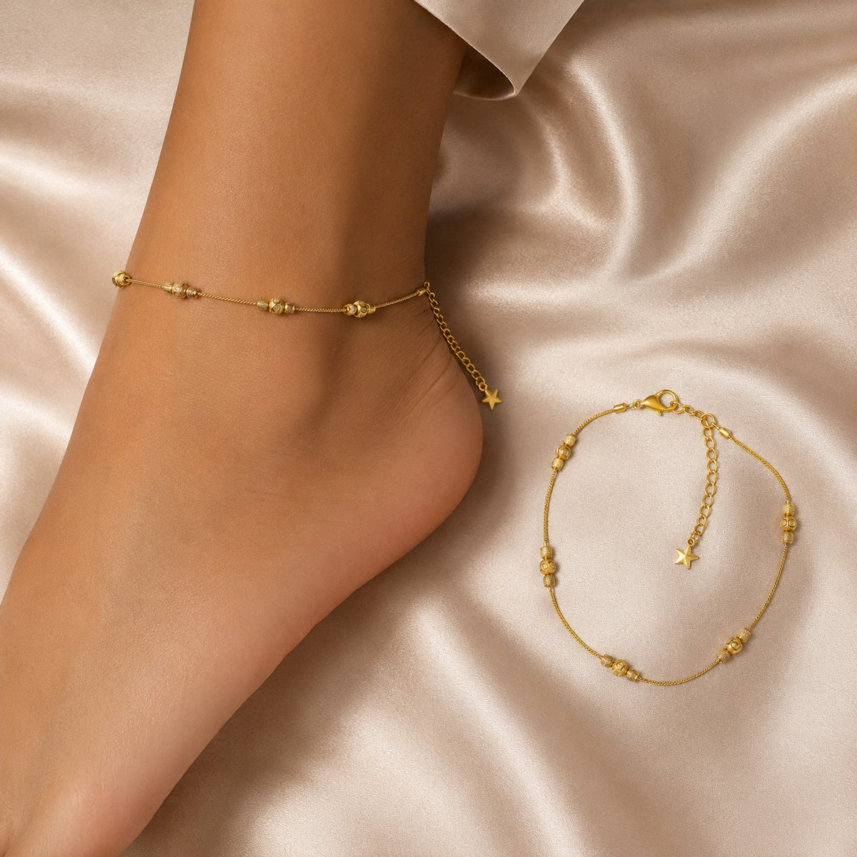 Gold-tone beaded anklet with star charm on model's ankle over satin background