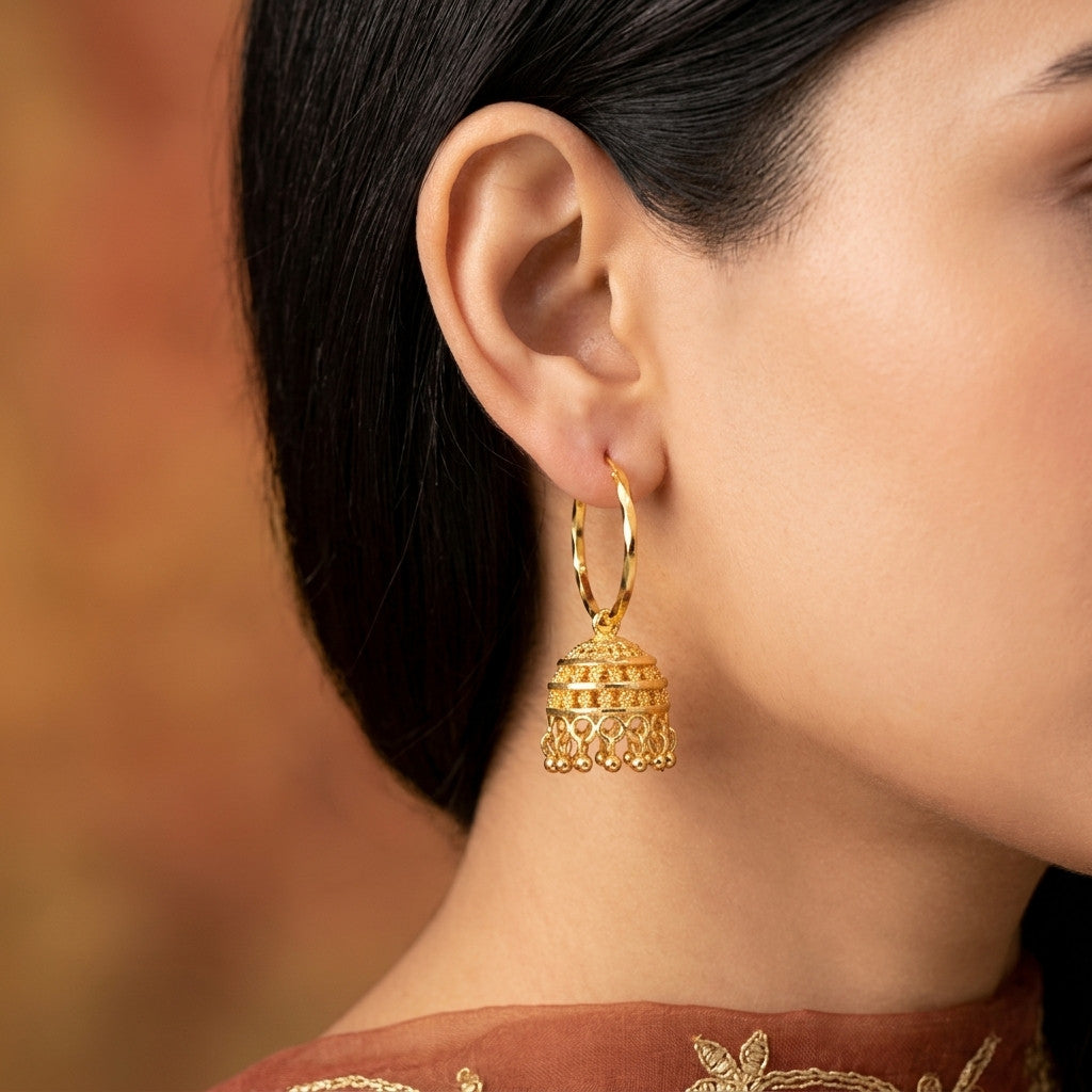 Model wearing gold-tone hoop earrings with jhumka pendant
