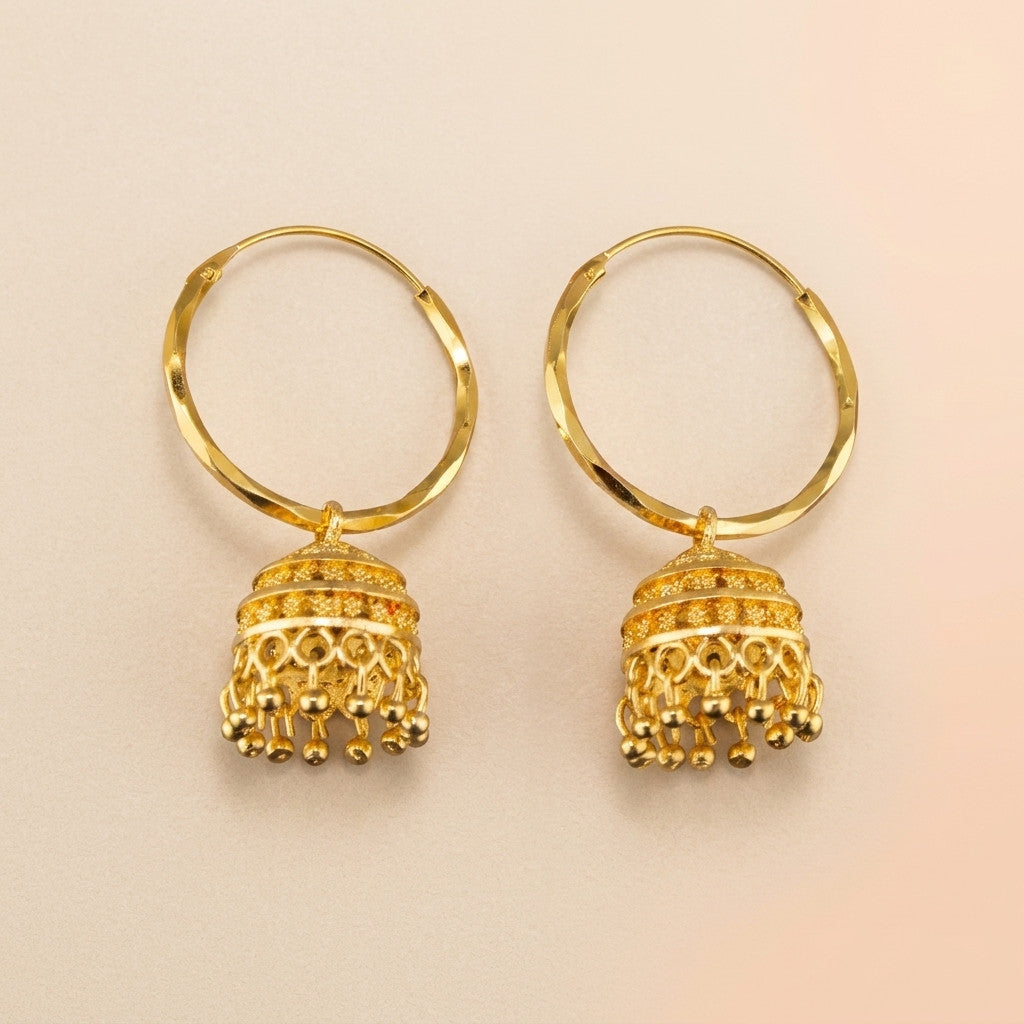 Pair of gold-tone hoop earrings with jhumka pendants on beige background