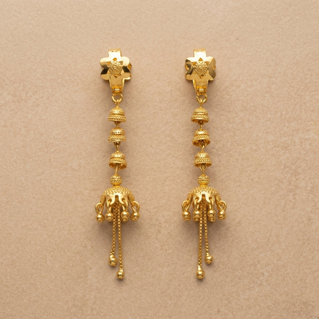 Pair of gold-tone jhumka style drop earrings on beige background