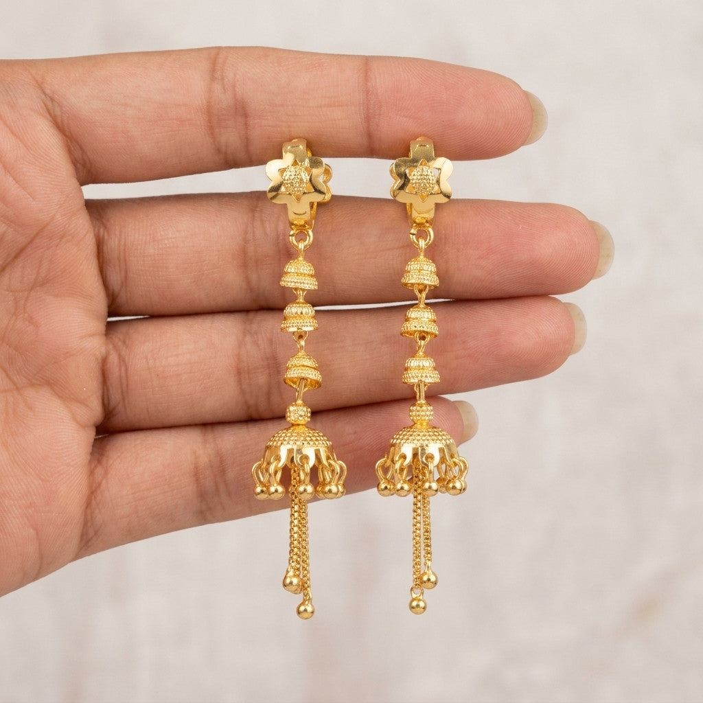 Gold-tone jhumka style drop earrings held in hand