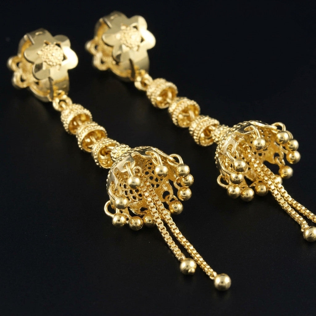 Close-up of gold-tone jhumka style drop earrings on black surface