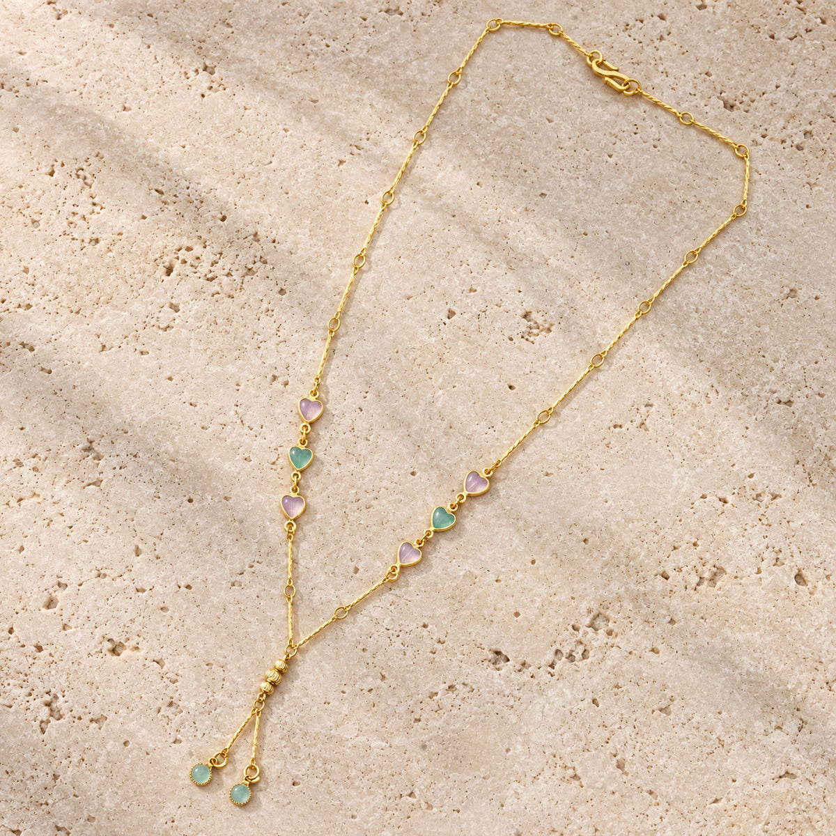 Gold-tone necklace laid flat showing heart details and Y-shaped drop