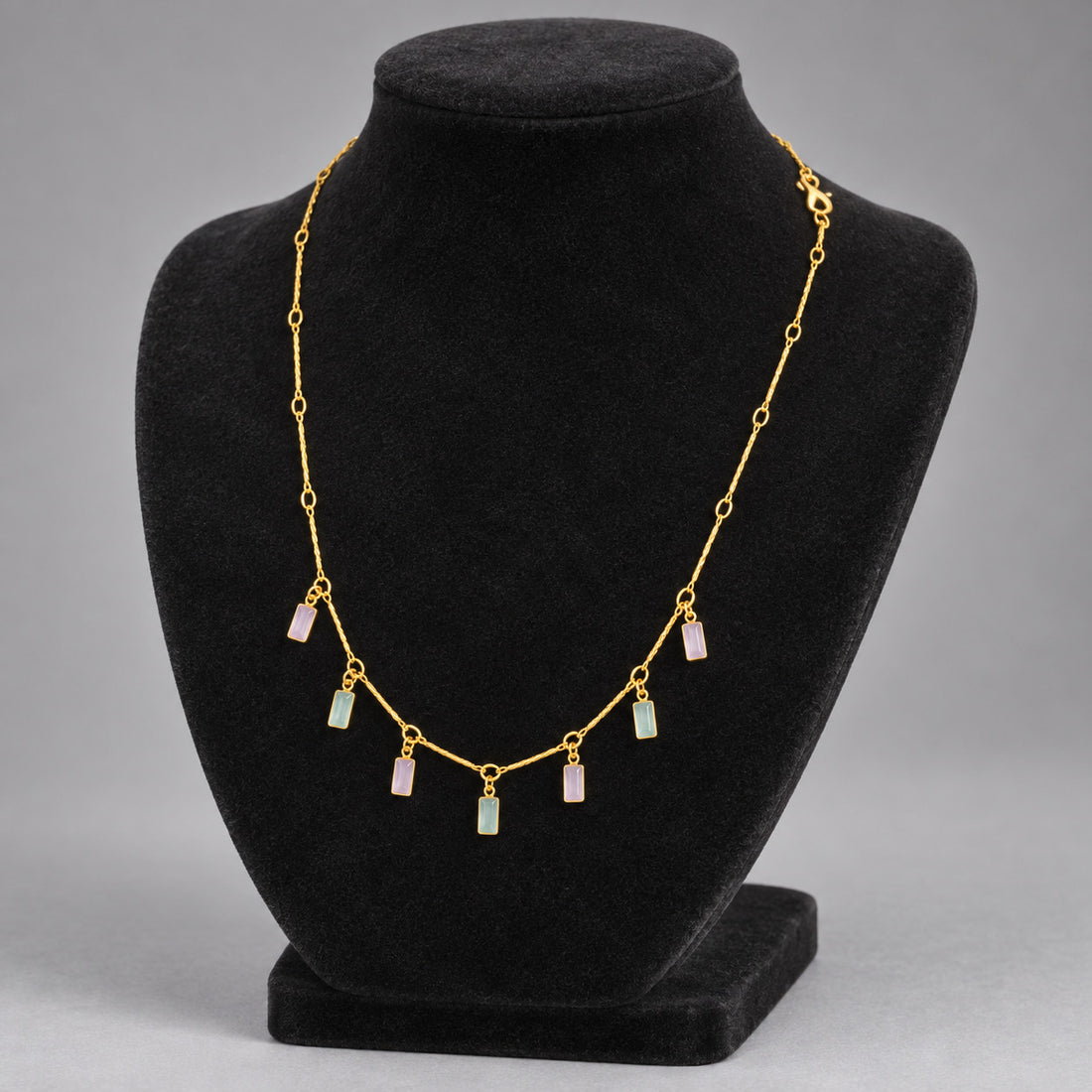 Woman wearing necklace with gold-tone chain and pastel rectangular charms alternating pink and green