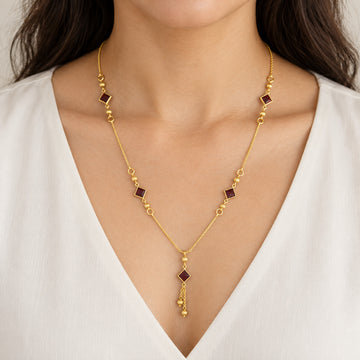 Gold-tone necklace with red square stone-look accents worn on model