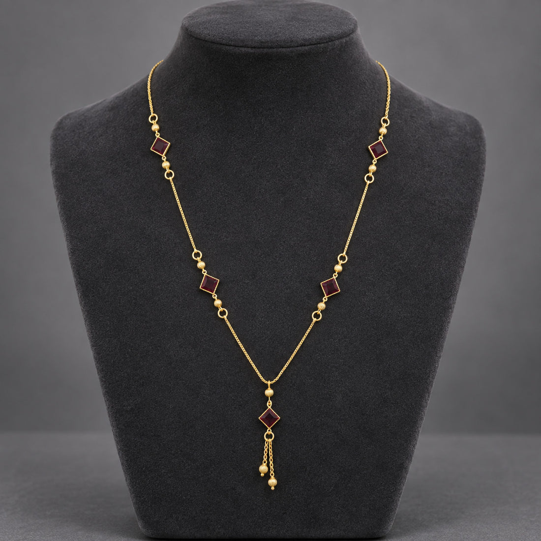 Gold-tone necklace with red square stone-look accents worn on model