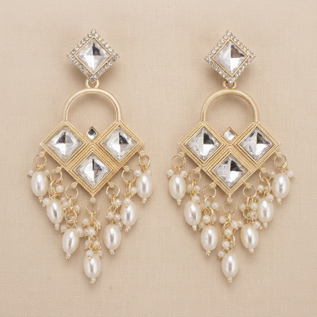 Close-up of gold-tone earrings with clear stone-look details and dangling pearl-look beads