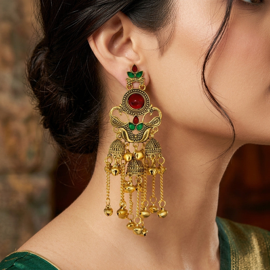 Close-up of model wearing gold-tone jhumka earrings with red and green accents