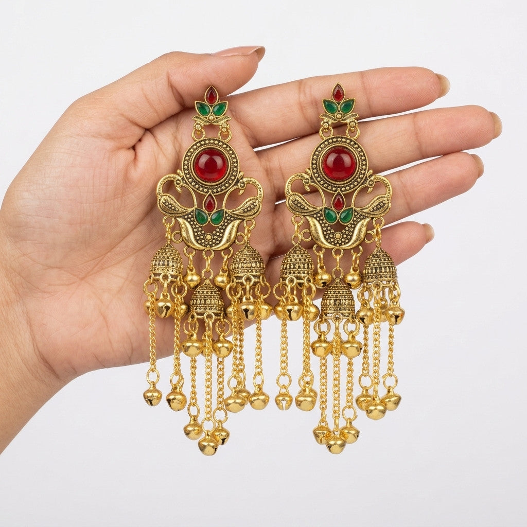 Close-up of model wearing gold-tone jhumka earrings with red and green accents