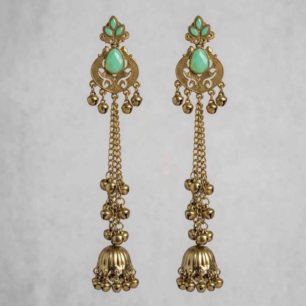 Pair of long antique gold-tone earrings with green stone accents on grey background
