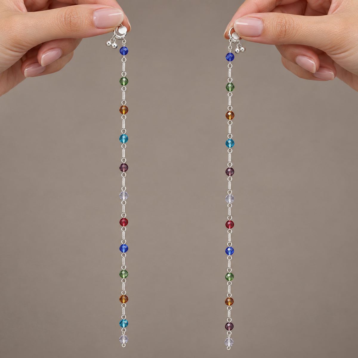 Hands holding both ends of silver-tone multicolour beaded anklets