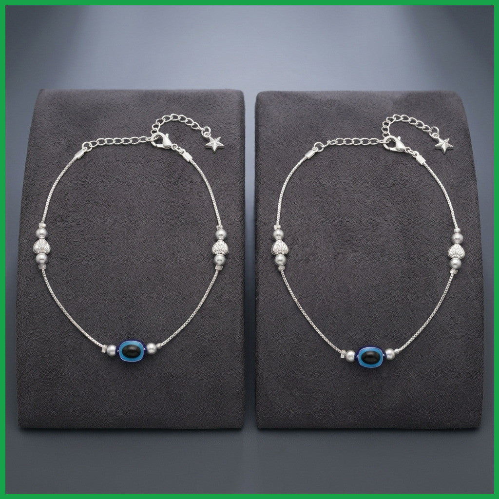 Two silver-tone anklets laid flat on display stand highlighting bead and chain details
