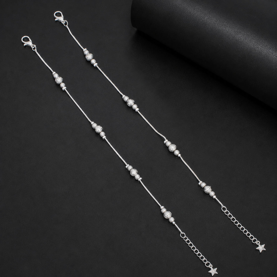 Silver-tone beaded anklet worn on ankle showing star charm extender