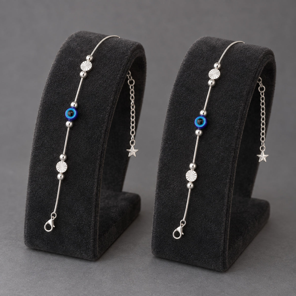 Silver-tone anklet with blue evil eye charm displayed on black stand