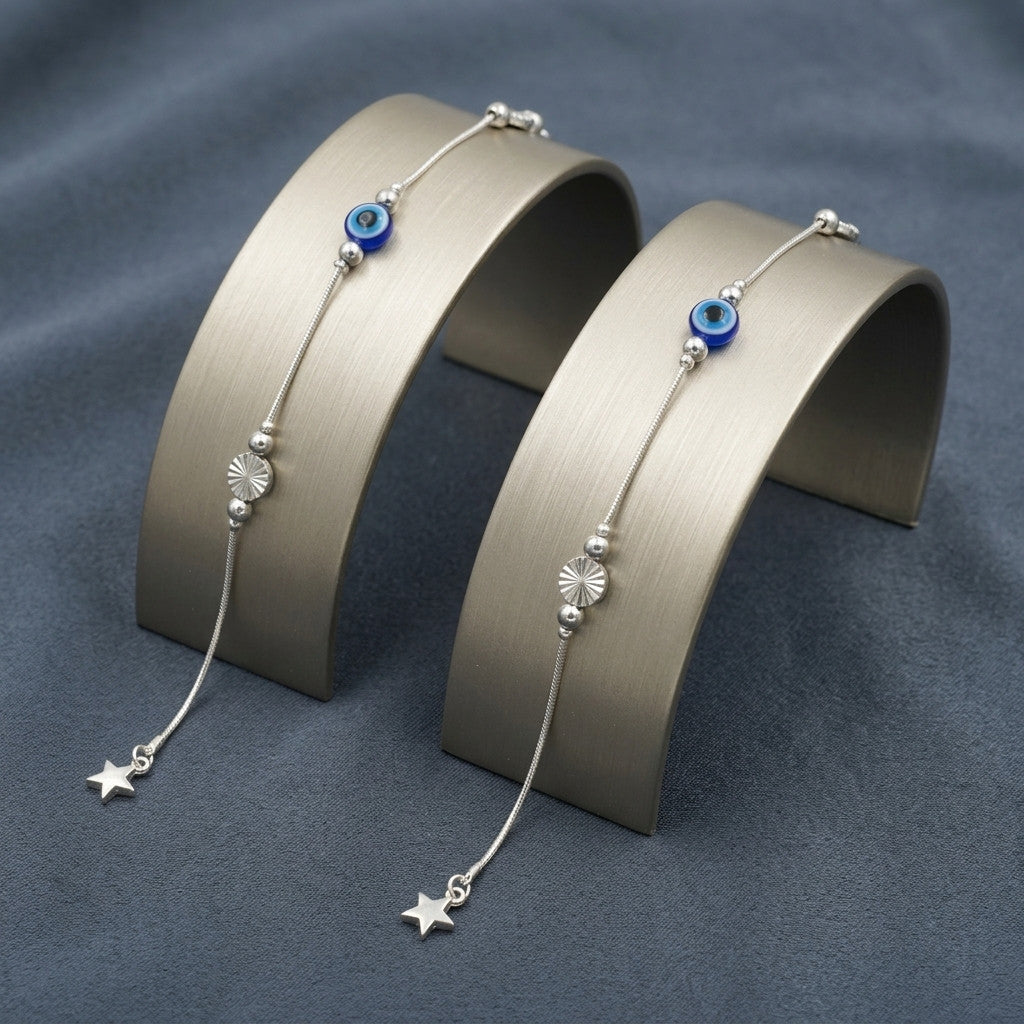 Close-up of silver-tone anklet with blue evil eye and star charm on metal display