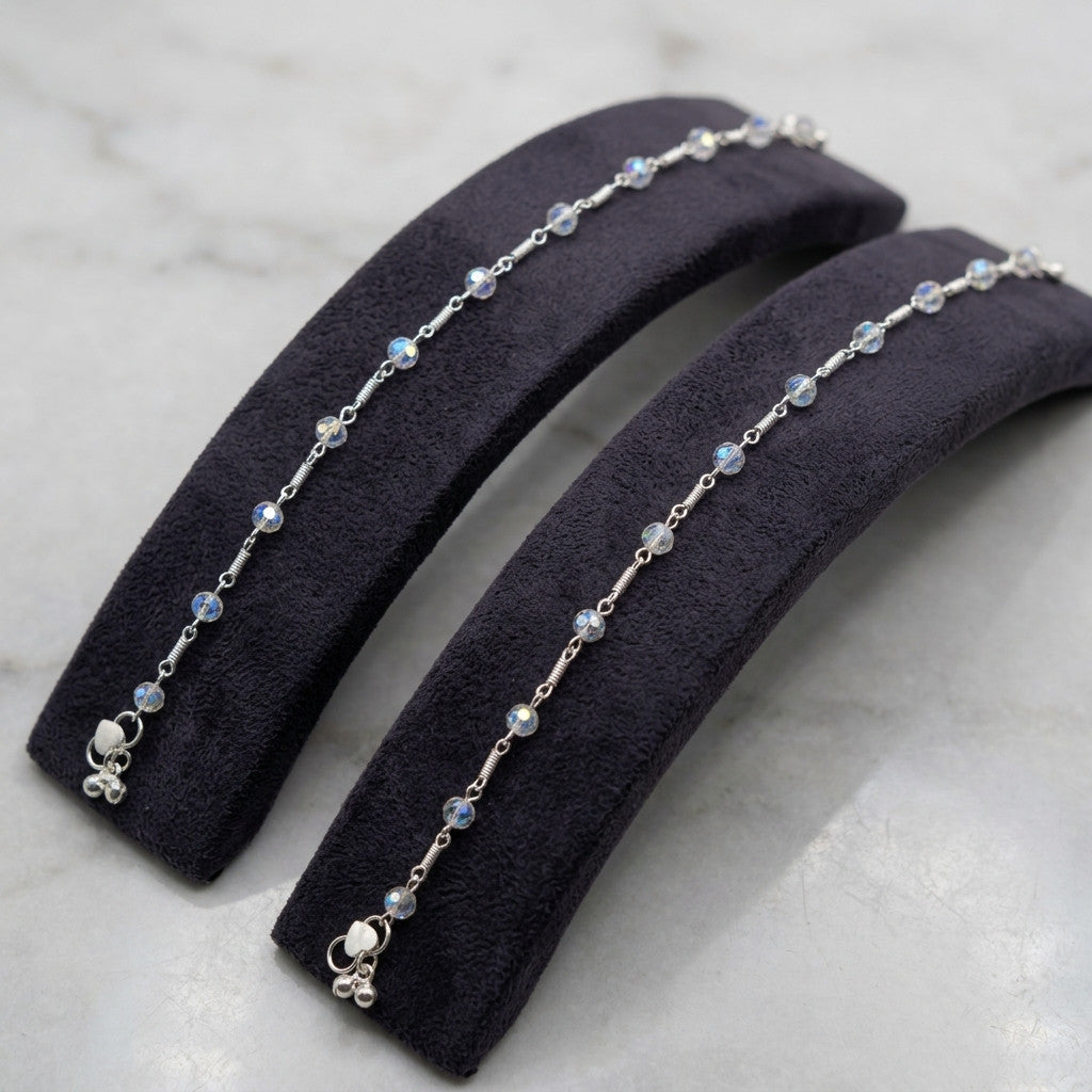 Pair of silver-tone crystal bead anklets displayed on black cushion