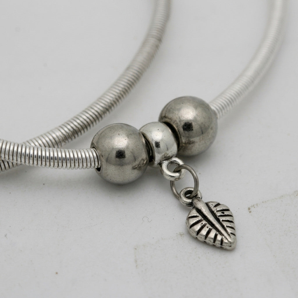 detailed view of silver-tone leaf charm on anklet