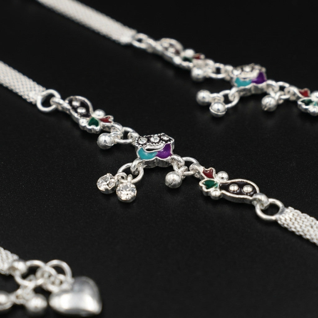 Close detail of silver-tone mesh chain and multicolor dangling charms on black background