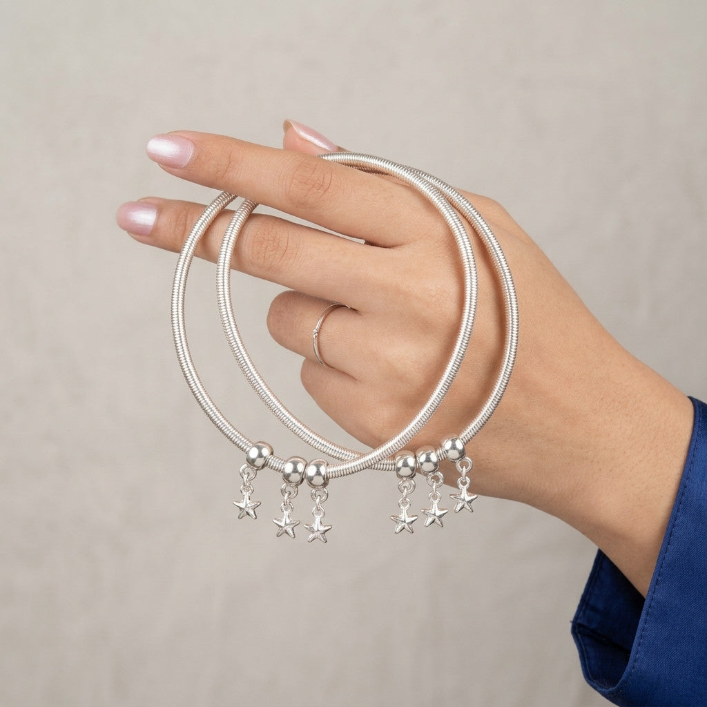 Silver-tone snake chain anklet worn on ankle with three star-shaped charms