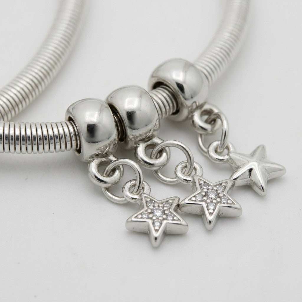 Close-up of three star-shaped charms hanging on snake chain anklets