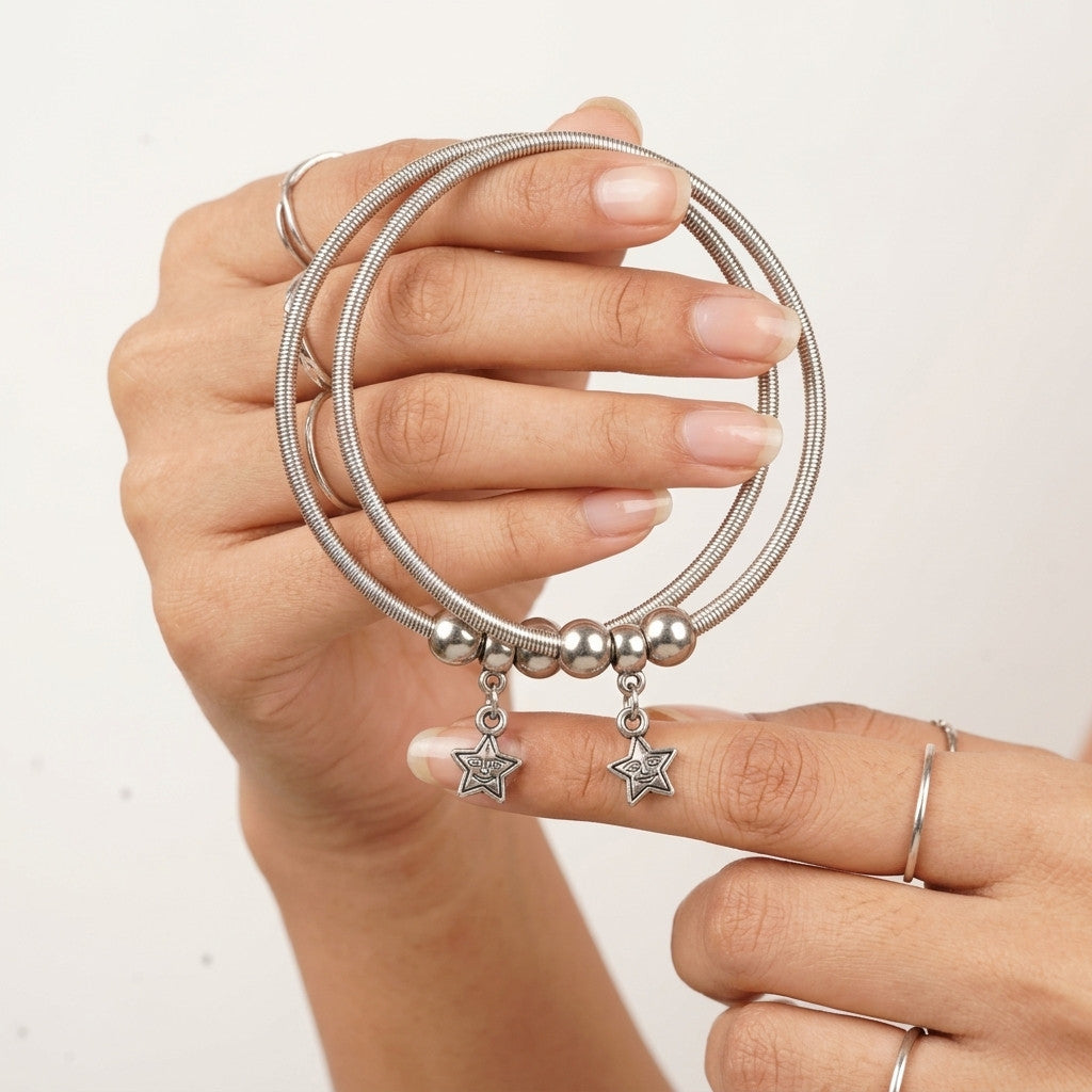 Close-up of hand holding two silver-tone star charm anklets